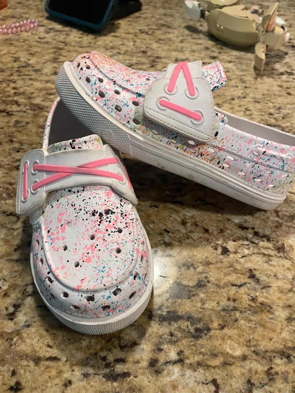Sperry White Kids Slip-On Shoes with Multicolor Paint-Splash and Pink Accents.